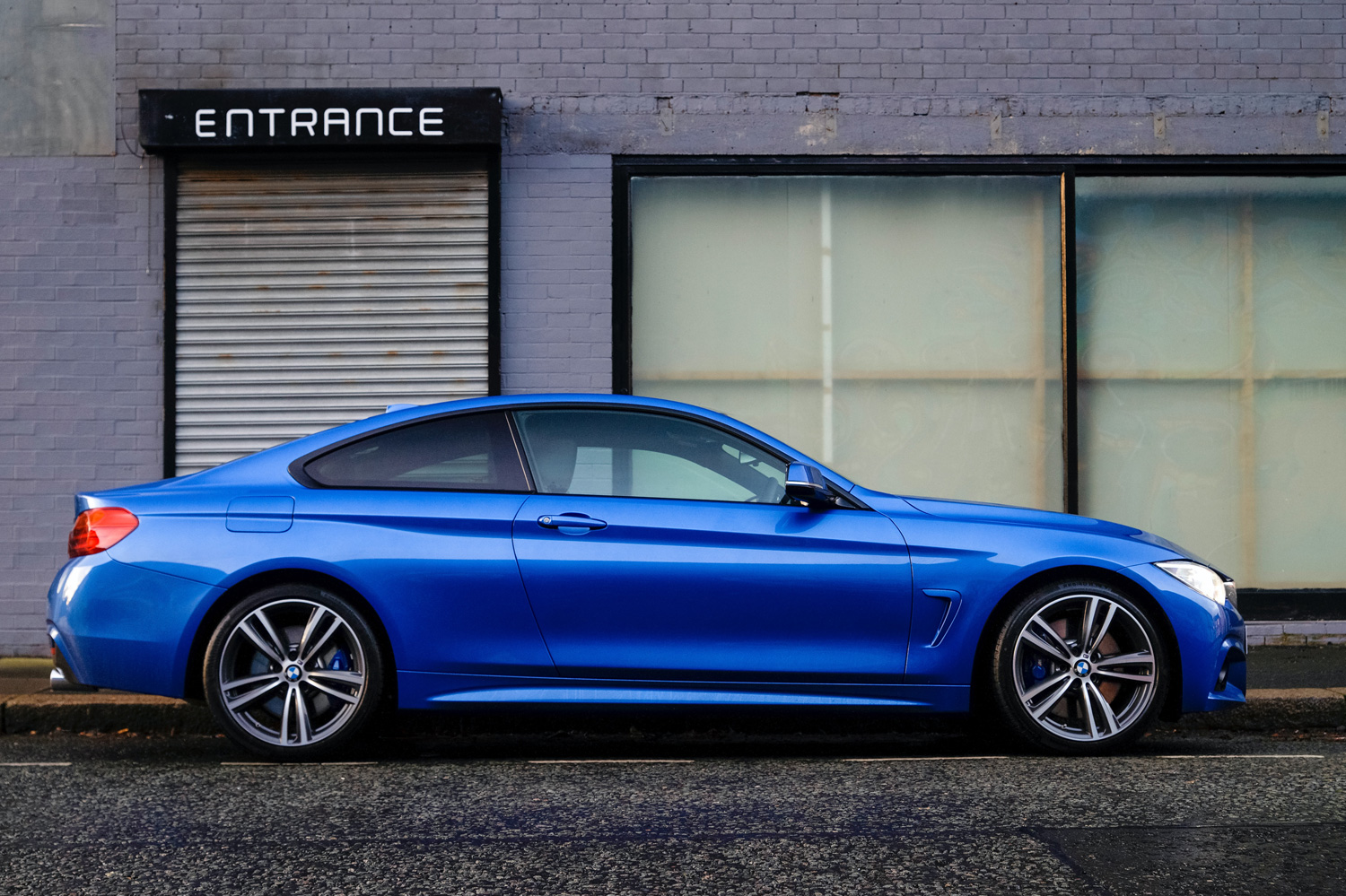 blue couple vehicle in front of a gray building