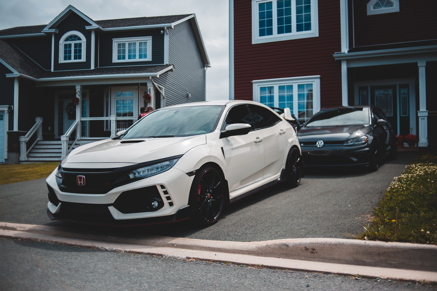 cars parked in the driveway next to houses