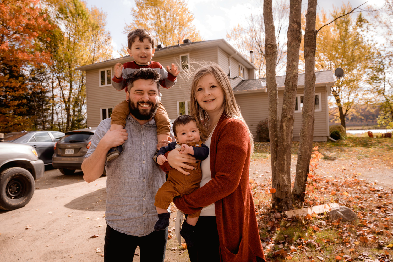 family smiling standing outside of a house