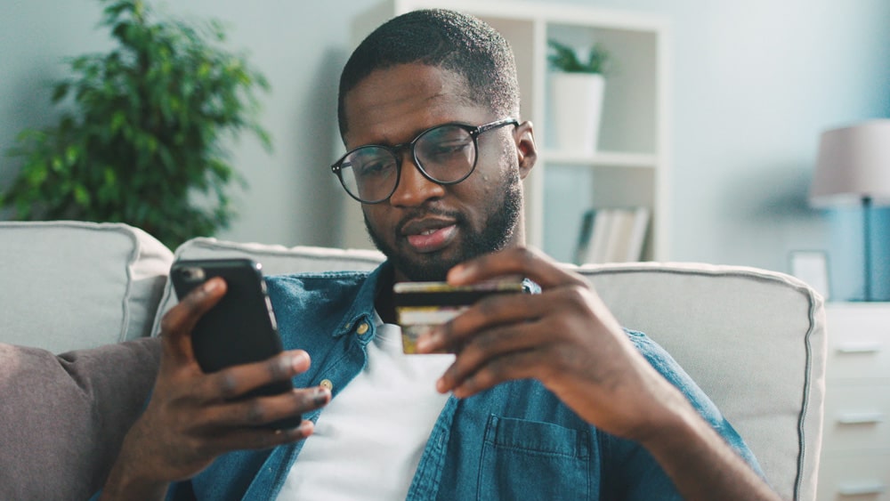 man holding credit card and mobile phone