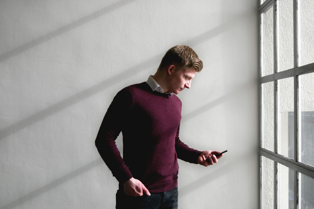 man standing holding and looking at his mobile phone