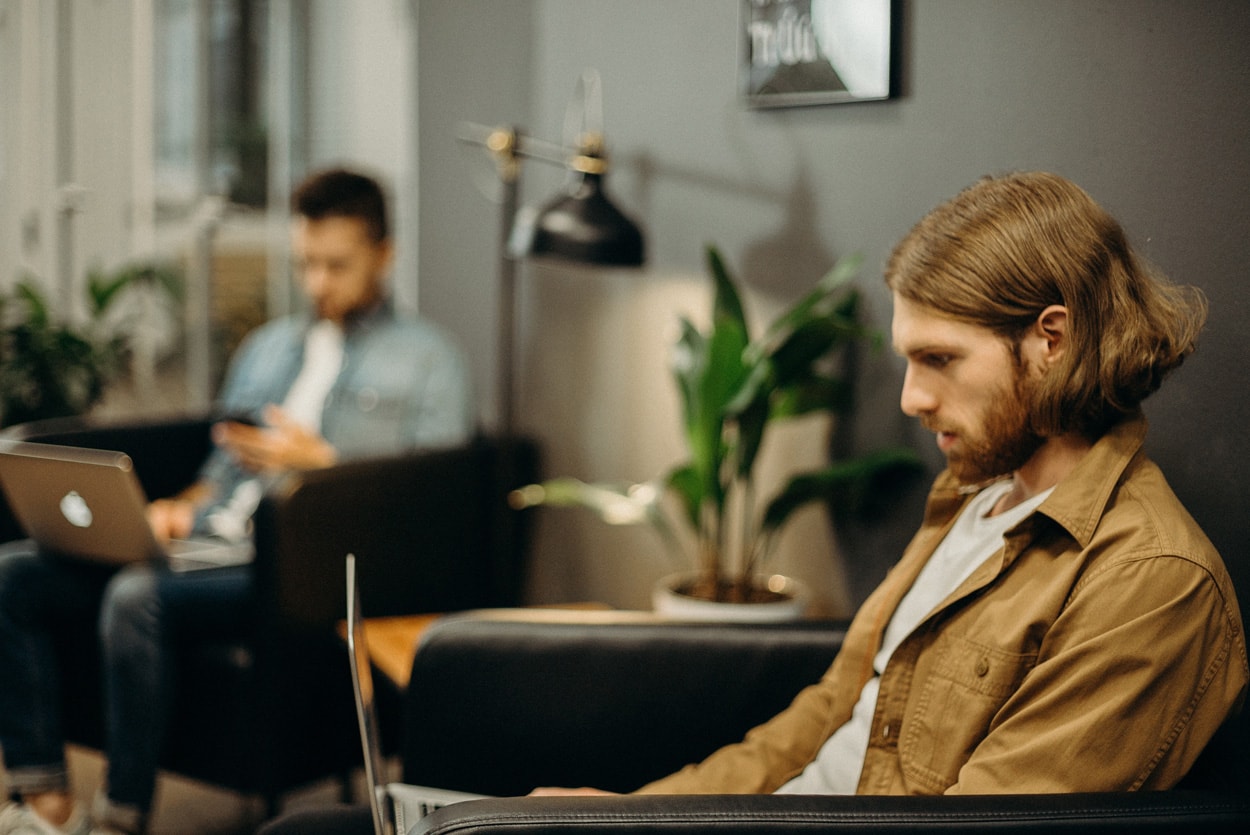 man in brown jacket sitting using laptop