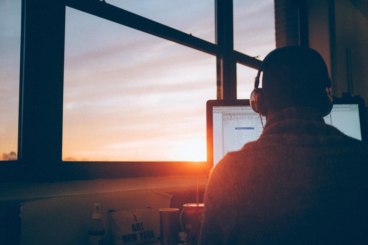 man sitting at a desk facing a computer monitor