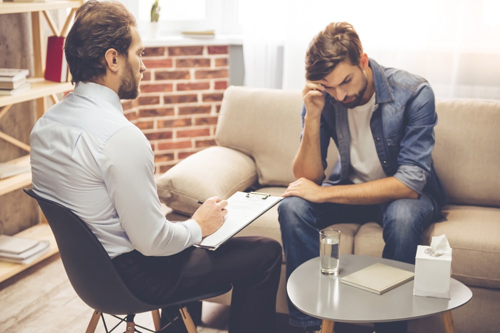 man sitting on couch and talking to psychologist