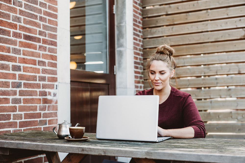 woman browsing on laptop sitting outside