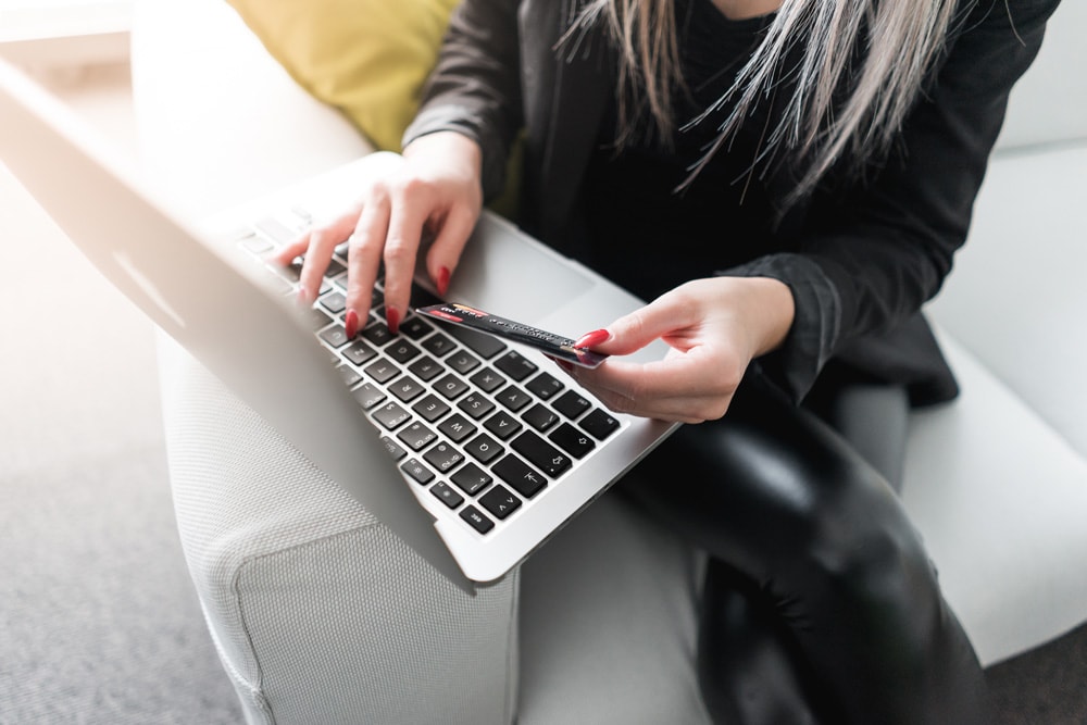 woman entering credit card information online on laptop