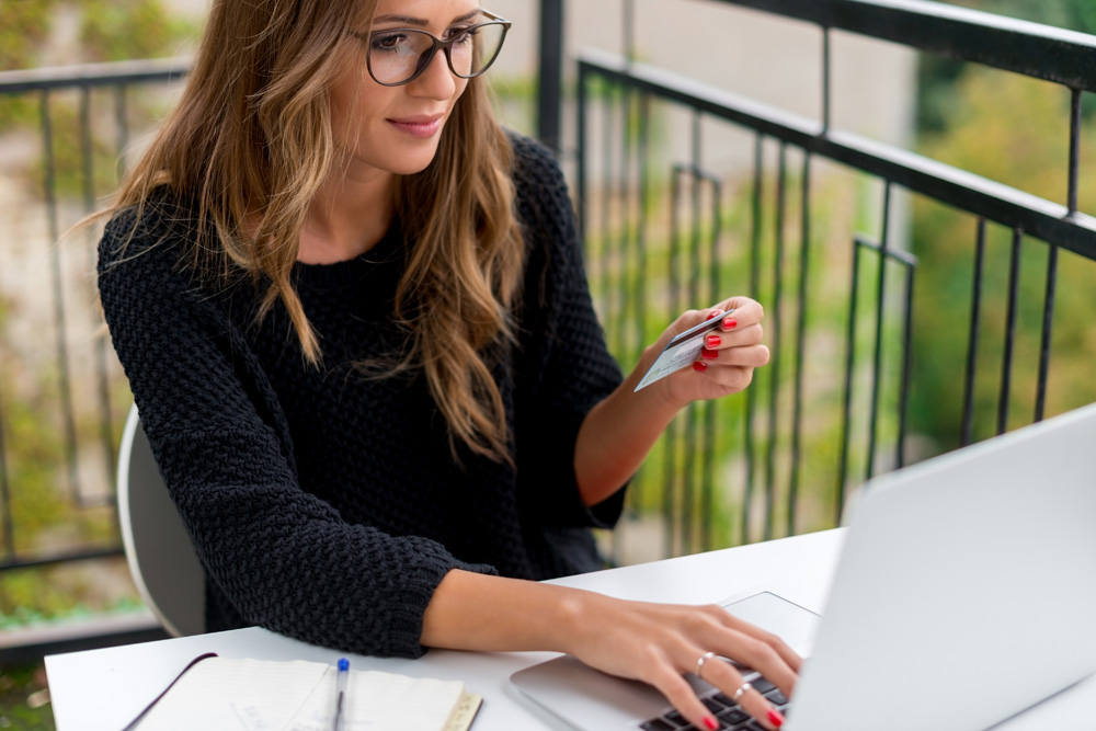 woman holding credit card browsing laptop