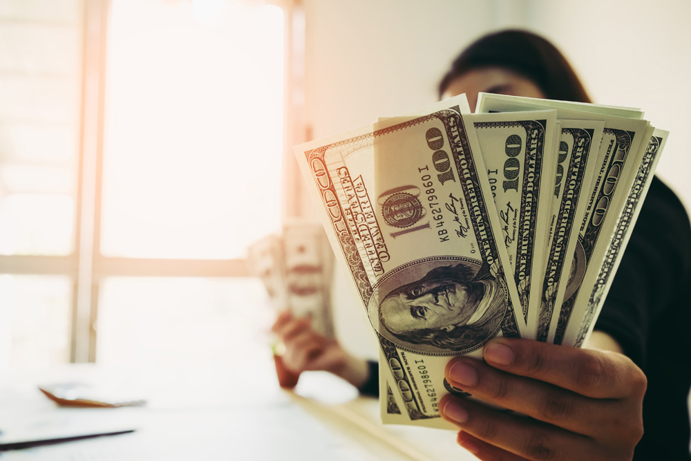 woman holding hundred dollar bills