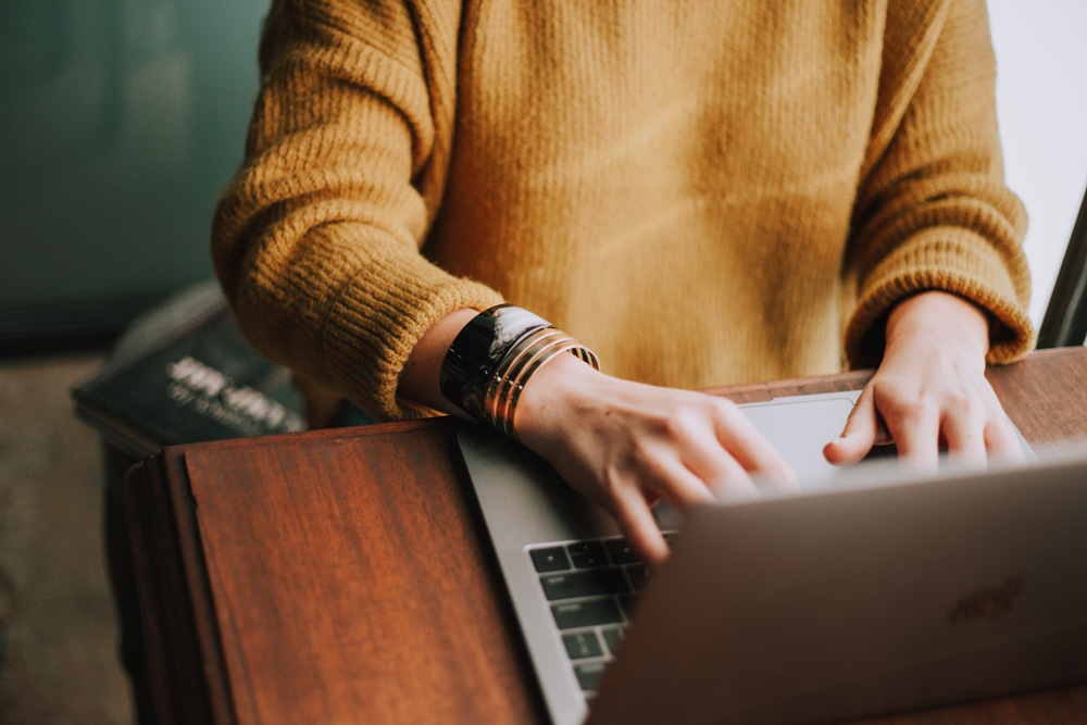 woman sitting at desk typing on a laptop